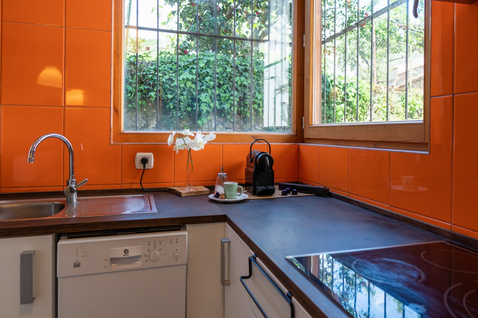 Cocina equipada con encimera oscura y ventana en la casa rural en Talaveruela de la Vera