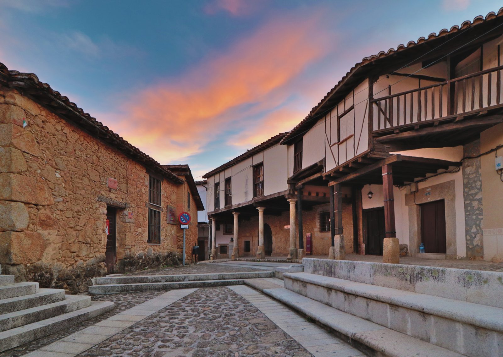 Plaza porticada de Cuacos de Yuste al atardecer, sede de las Veladas Culturales
